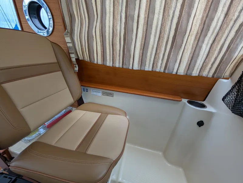 Slide: The Image of 2024 Ranger Tugs R27-OB interior with beige seating and striped curtains. - 18