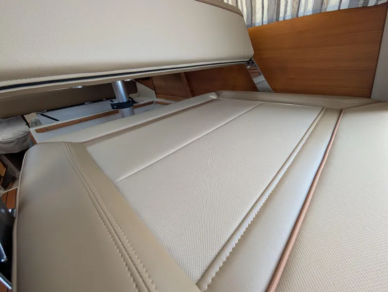 Slide: The Image of 2024 Ranger Tugs R27-OB interior seating with beige upholstery and wooden accents. - 19