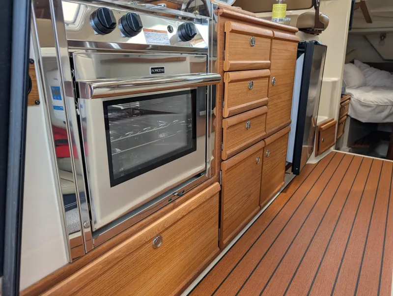 Slide: The Image of 2024 Ranger Tugs R27-OB interior kitchen with wood cabinetry and stainless steel oven. - 26