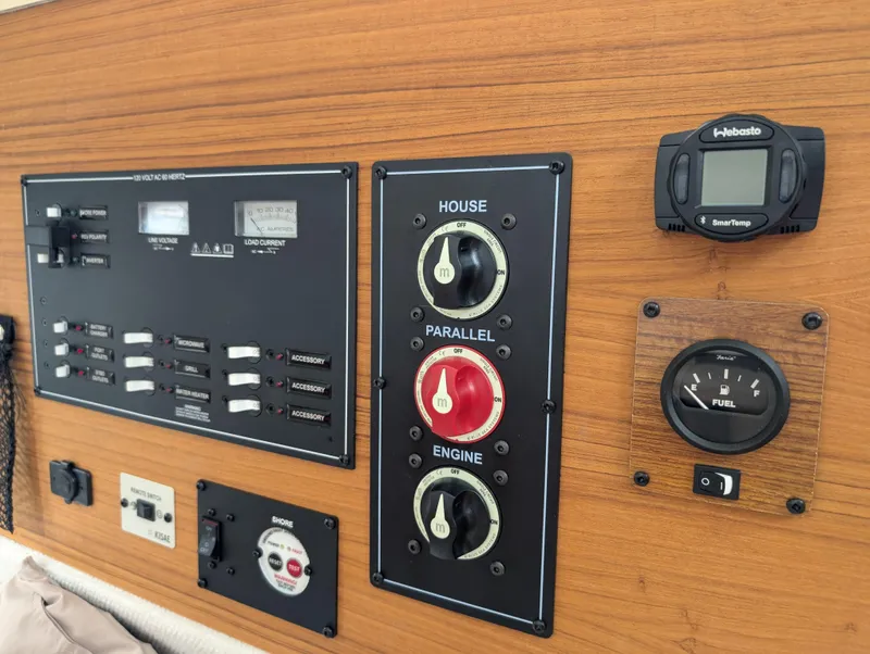 Slide: The Image of 2024 Ranger Tugs R27-OB control panel with switches and fuel gauge on wooden dashboard. - 27