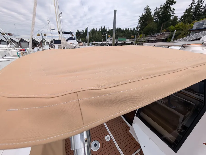 Slide: The Image of 2024 Ranger Tugs R27-OB boat with beige canvas cover, docked at marina. - 28