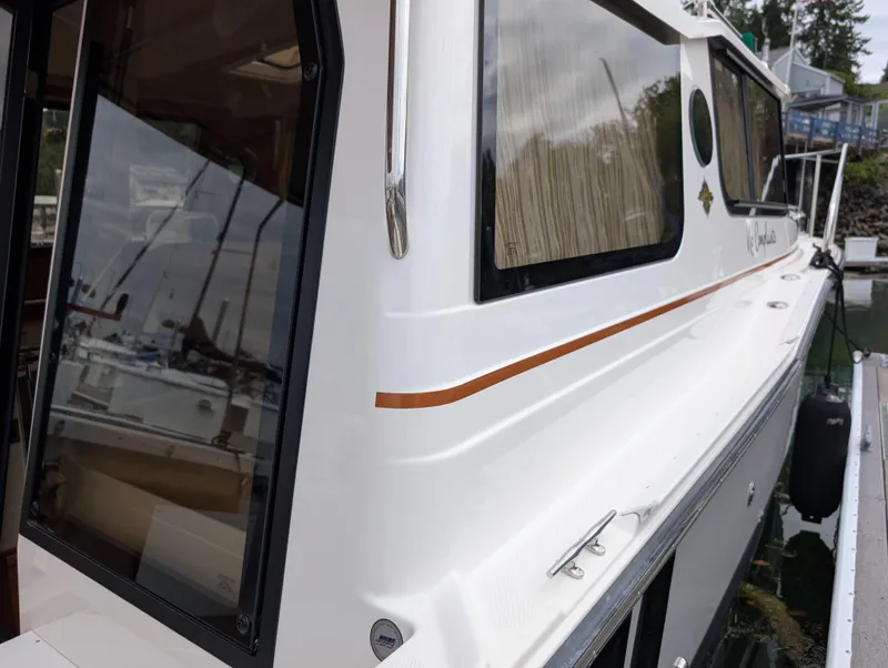 Slide: The Image of 2024 Ranger Tugs R27-OB boat docked, showcasing sleek design and large windows. - 5