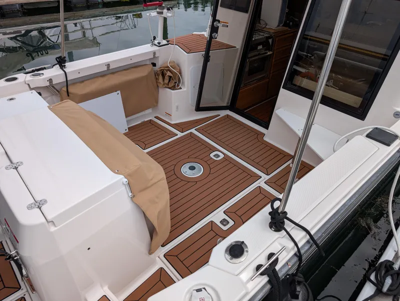 Slide: The Image of 2024 Ranger Tugs R27-OB boat deck with teak flooring and open cabin door. - 6