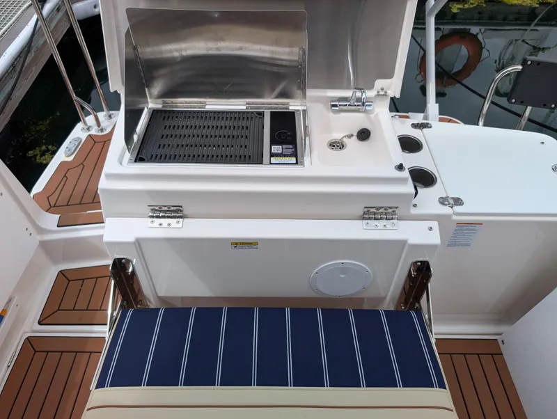 Slide: The Image of 2024 Ranger Tugs R27-OB boat with outdoor grill and seating area. - 9