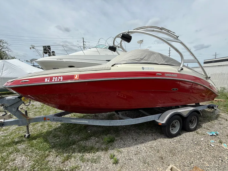 The Image of 2014 Yamaha Boats 242 Limited S in red on a trailer, parked outdoors. - 2