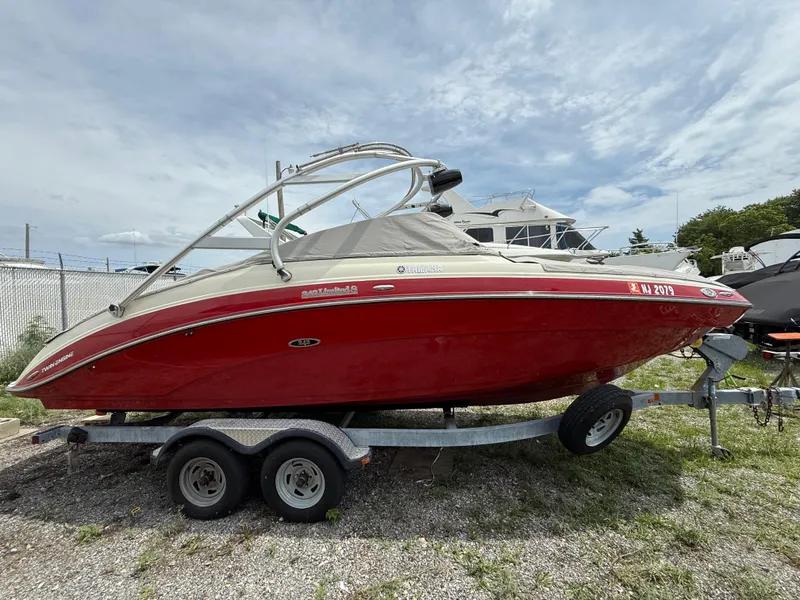 Slide: The Image of 2014 Yamaha Boats 242 Limited S in red on a trailer, parked outdoors. - 5