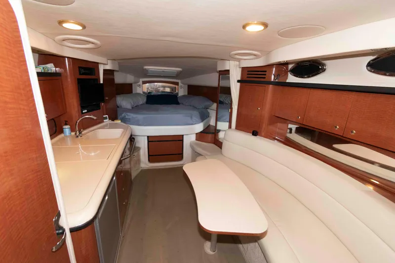 Slide: The Image of 2004 Sea Ray 340 Sundancer cockpit with white seating and table, docked by calm water. - 12