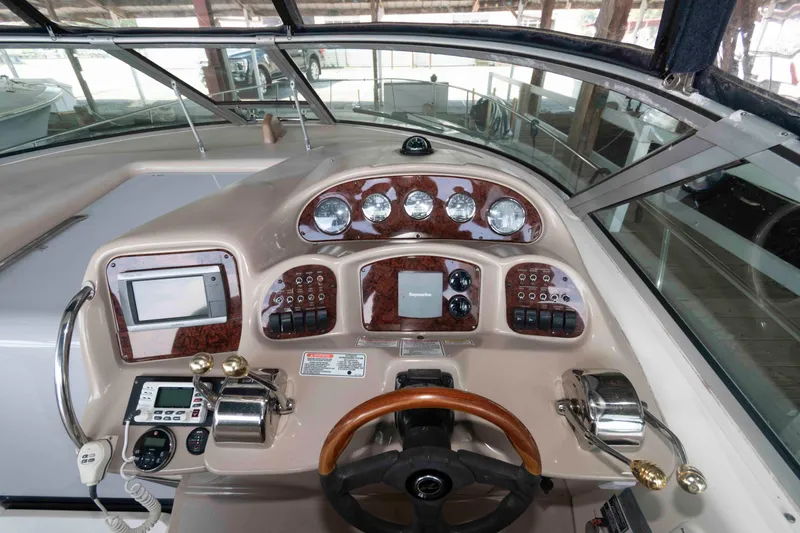 Slide: The Image of 2004 Sea Ray 340 Sundancer interior with white seating and table in a marina setting. - 8