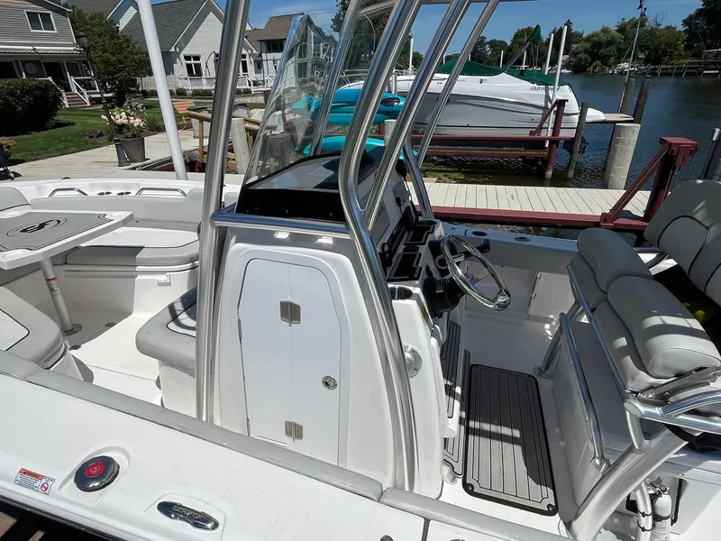 Slide: The Image of 2023 Sea Fox 248 Commander boat interior with helm, seating, and table, docked by waterfront homes. - 8