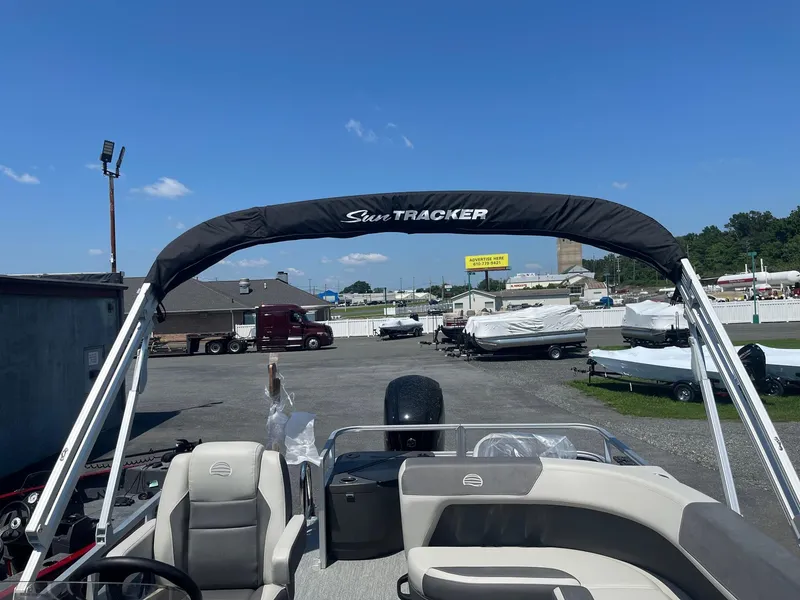 Slide: The Image of 2026 Sun Tracker Bass Buggy 18 DLX pontoon boat with canopy in a dealership lot. - 4