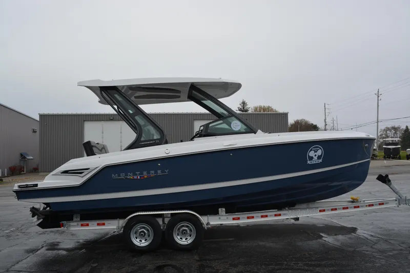 Slide: The Image of 2026 Monterey Elite 25 SD boat on trailer, blue and white design, parked outdoors. - 7