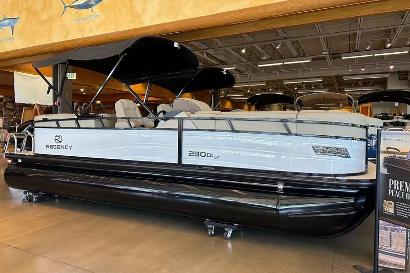Slide: The Image of 2025 Regency 230 DL3 pontoon boat displayed indoors with sleek design and canopy. - 1