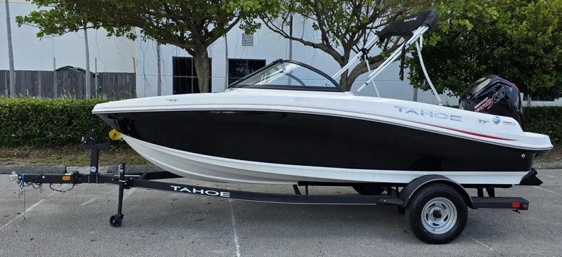 The Image of 2024 Tahoe 185 S boat on trailer, black and white design, parked outdoors. - 0