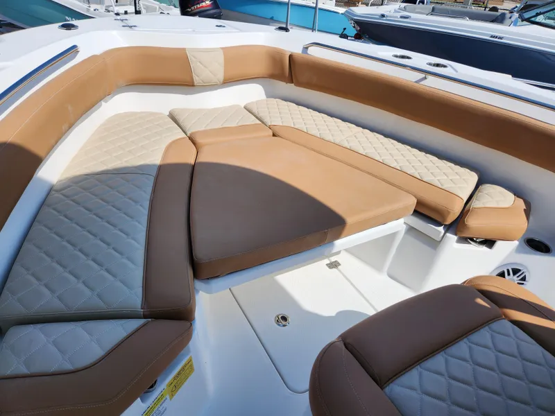 Slide: The Image of 2025 NauticStar 222 OSL boat interior with tan and cream cushioned seating. - 10