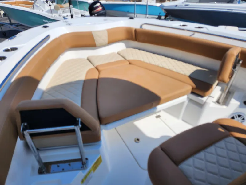 Slide: The Image of 2025 NauticStar 222 OSL boat interior with tan cushioned seating and white deck. - 11