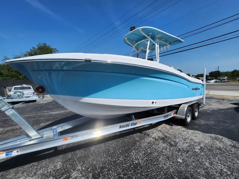 Slide: The Image of 2025 NauticStar 222 OSL boat on trailer, blue and white design, sunny day. - 14