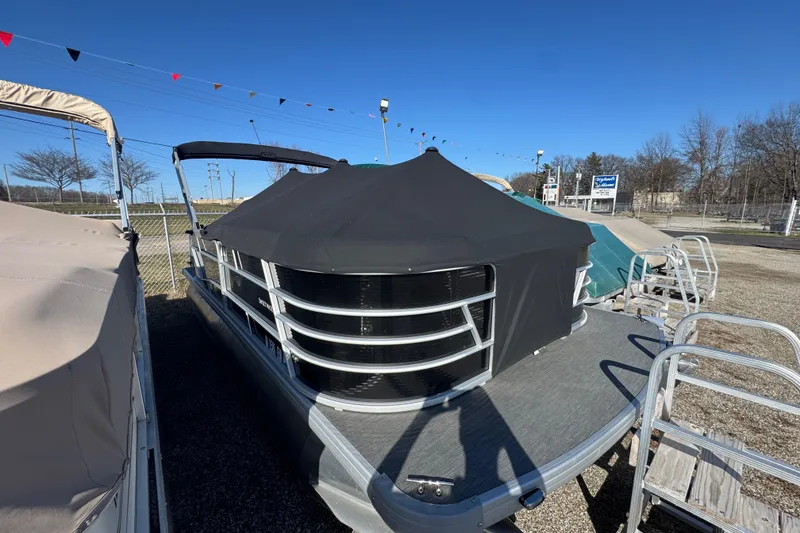 Slide: The Image of 2023 Sweetwater SW2086c pontoon boat with cover, parked outdoors under clear blue sky. - 11