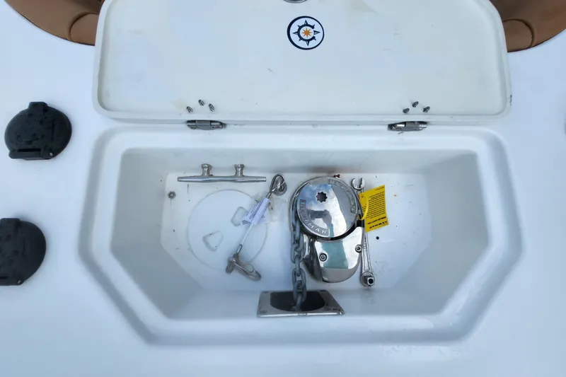 Slide: The Image of Anchor compartment of 2026 NauticStar 252 Legacy boat, featuring a windlass and chain. - 14
