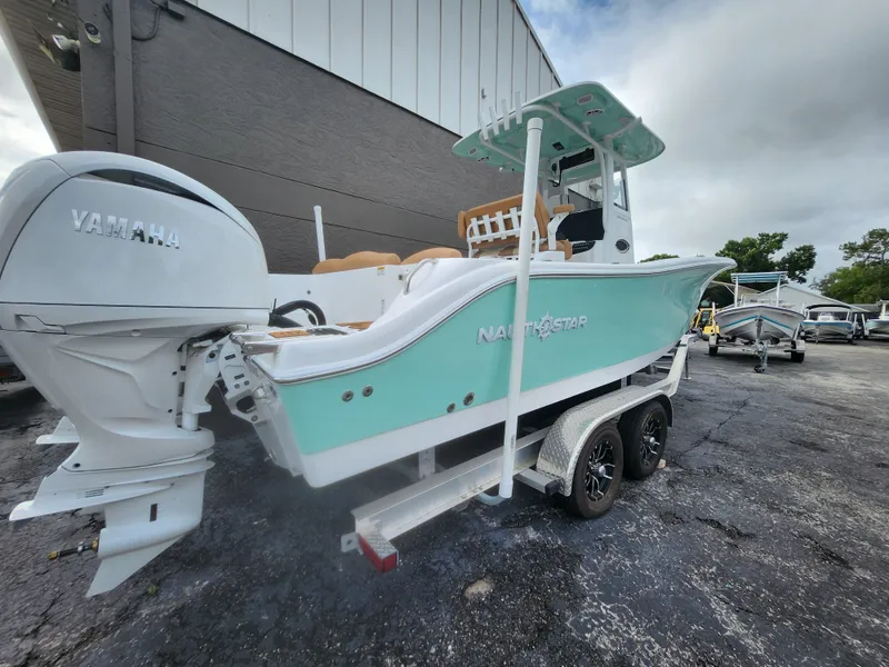 Slide: The Image of 2026 NauticStar 252 Legacy boat with Yamaha engine on trailer, parked outdoors. - 2