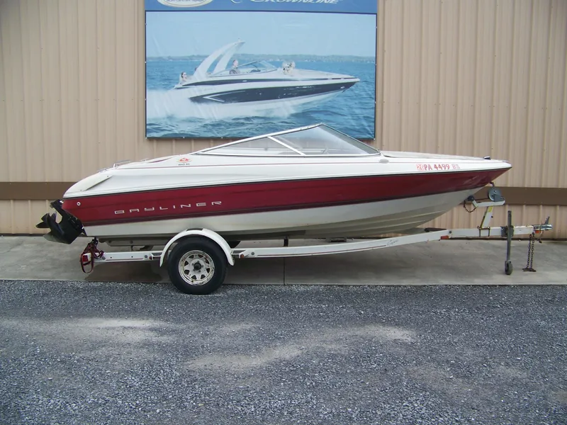 The Image of 1996 Bayliner 1850SS boat on trailer, red and white design, parked outside. - 1