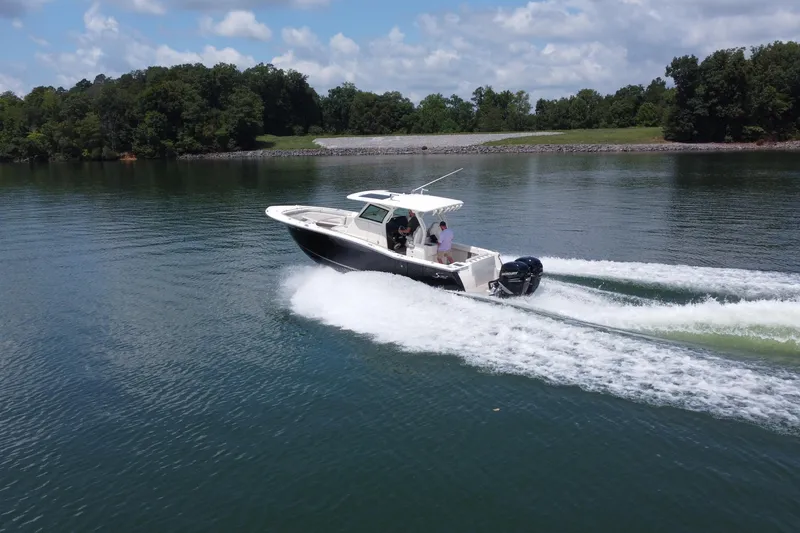 Slide: The Image of 2021 Scout 330 LXF boat cruising on a serene lake under a partly cloudy sky. - 9
