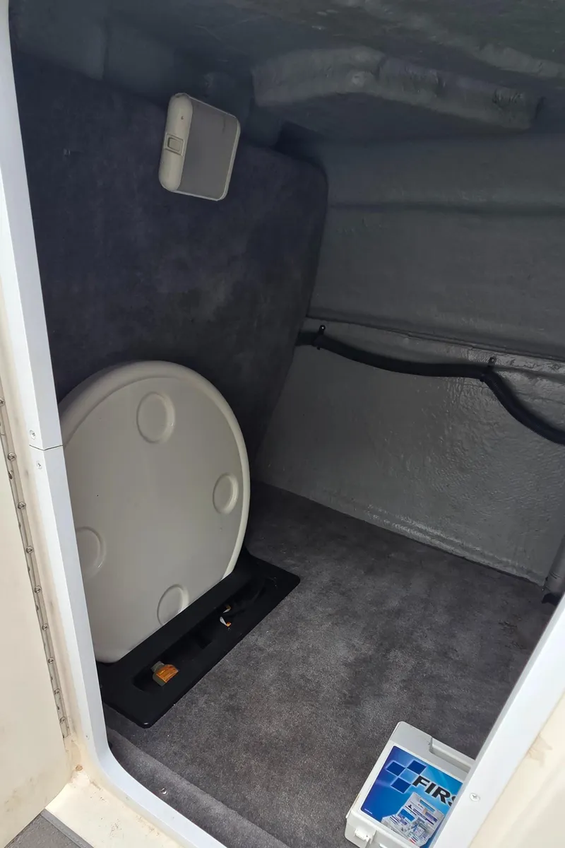 Slide: The Image of Interior cabin of a 2004 Monterey 233 Explorer boat, featuring storage space and carpeted flooring. - 15