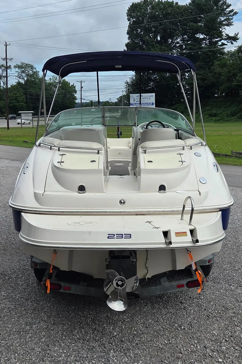 Slide: The Image of 2004 Monterey 233 Explorer boat, rear view, parked on gravel with canopy and dual seating. - 3