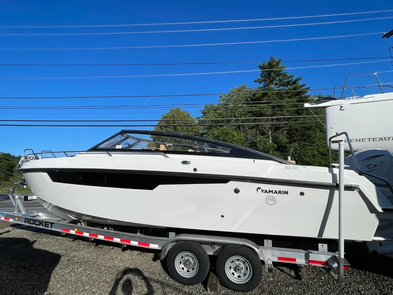 Slide: The Image of 2023 Yamarin 88 DC boat on trailer under clear blue sky. - 2