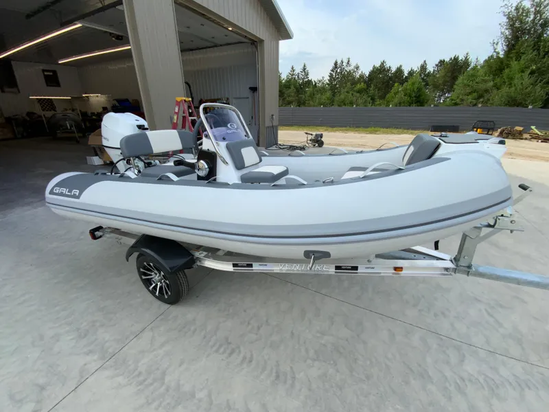 Slide: The Image of 2026 Gala A330L inflatable boat on trailer, parked outside a garage. - 8