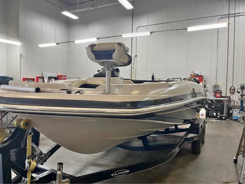 Slide: The Image of 2010 Tahoe 195 Deckboat in a workshop, on a trailer, under bright lights. - 10