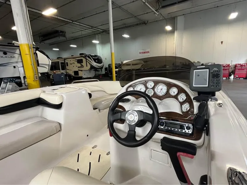 Slide: The Image of Interior of a 2010 Tahoe 195 Deckboat with steering wheel and dashboard in a warehouse. - 12