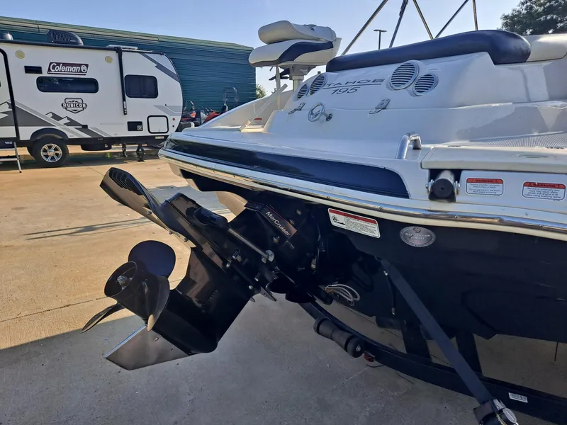 Slide: The Image of 2010 Tahoe 195 Deckboat with outboard motor, parked near a Coleman camper. - 13