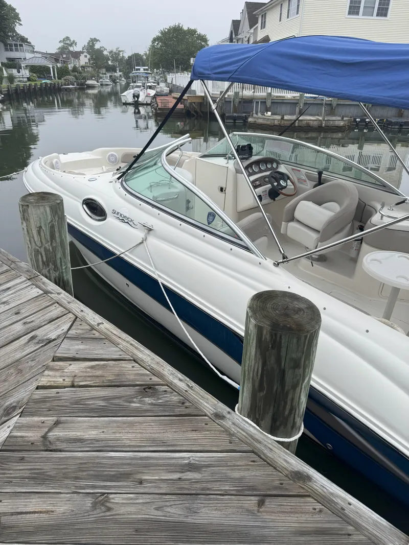 The Image of 2004 Sea Ray 240 Sundeck boat docked with blue canopy and white interior. - 0