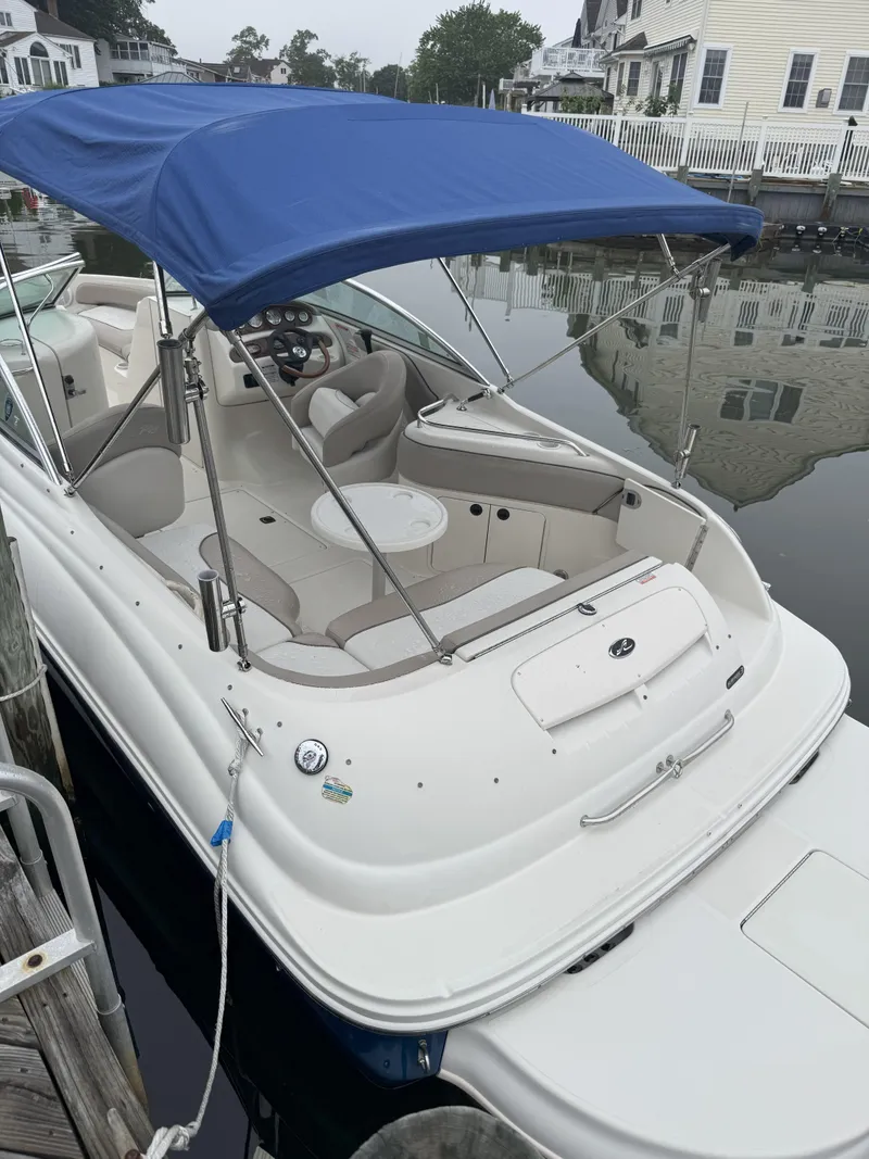 Slide: The Image of 2004 Sea Ray 240 Sundeck boat with blue canopy docked by waterfront homes. - 2