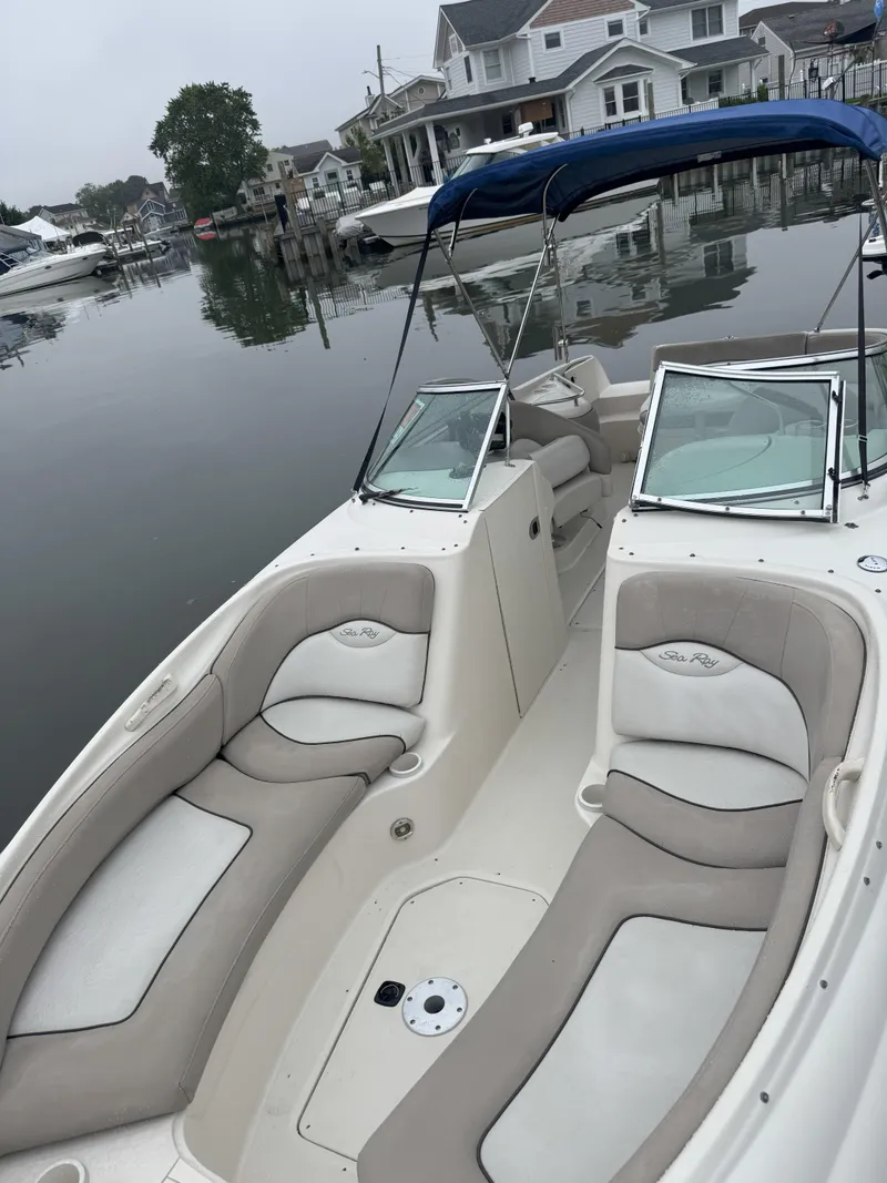 Slide: The Image of 2004 Sea Ray 240 Sundeck boat with spacious seating, docked near waterfront homes. - 3