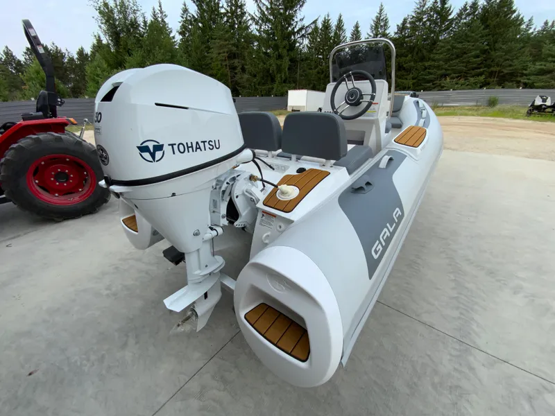 Slide: The Image of 2026 Gala V330 inflatable boat with Tohatsu engine, parked outdoors near trees. - 3