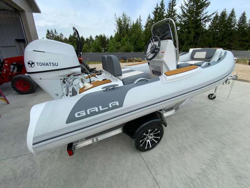 Slide: The Image of 2026 Gala V330 boat with Tohatsu engine on a trailer, parked outdoors. - 5