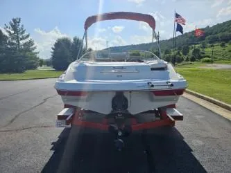 Slide: The Image of 2008 Crownline 19 SS boat on trailer, parked outdoors with flags and trees in background. - 3