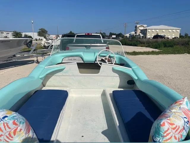 Slide: The Image of 1959 Glastron 15' Surflite boat with blue seats and pastel interior, parked outdoors. - 6