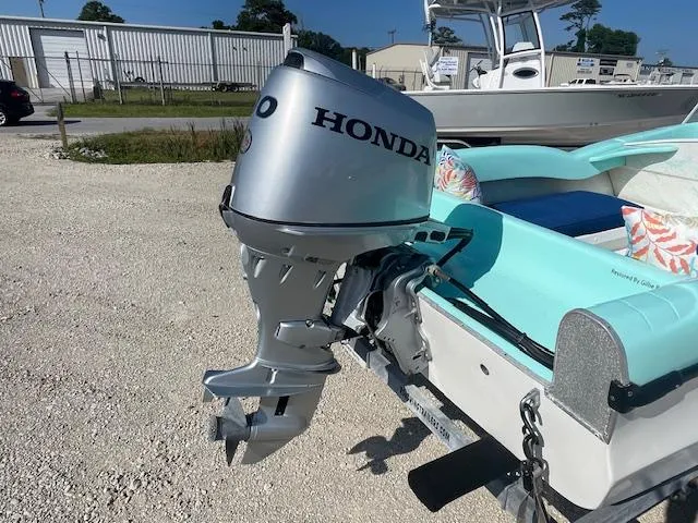 Slide: The Image of 1959 Glastron 15' Surflite boat with Honda outboard motor, parked on gravel. - 8