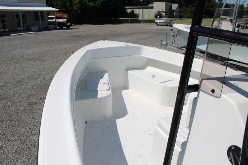 Slide: The Image of 2025 C-Hawk 19CC boat interior with seating and storage, parked outdoors. - 16