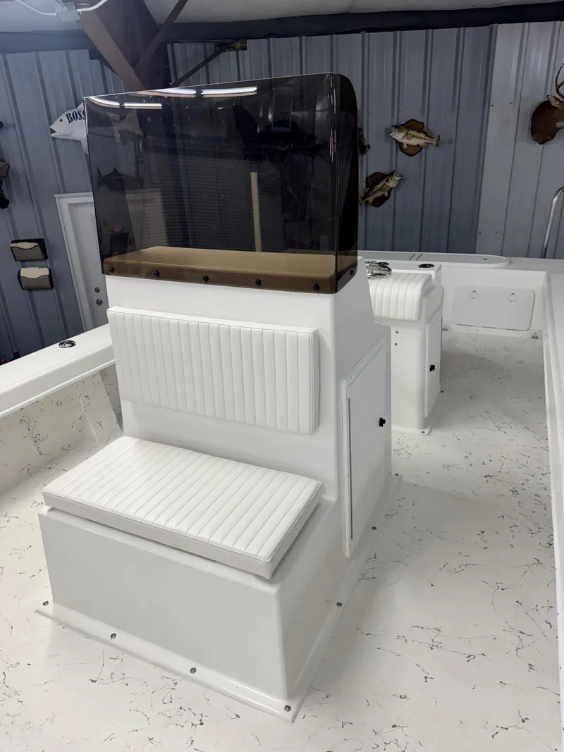 Slide: The Image of 2026 C-Hawk 25 boat interior with white seating and tinted windshield in a garage setting. - 12