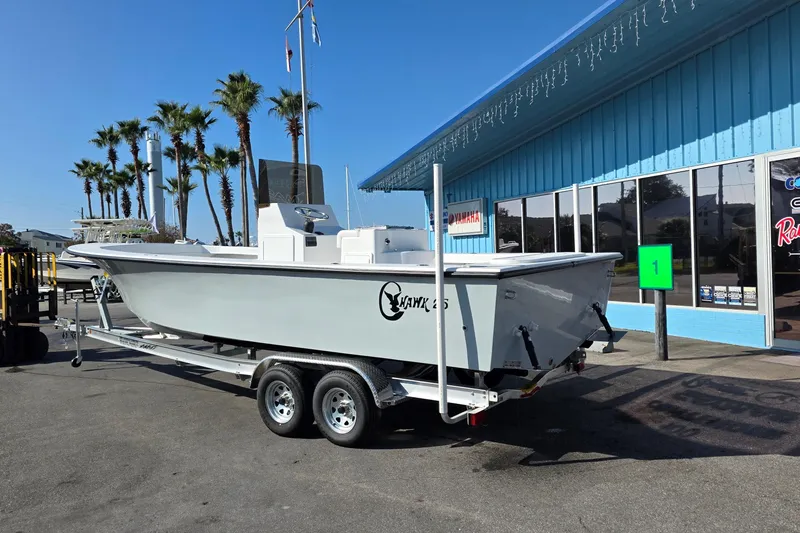 Slide: The Image of 2026 C-Hawk 25 boat on trailer outside a blue building with palm trees. - 5