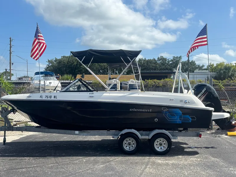 The Image of 2018 Bayliner Element F21 boat on trailer with American flags, parked outdoors. - 12