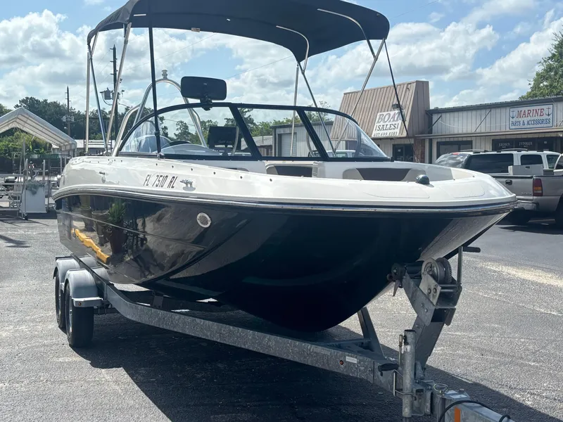 Slide: The Image of 2018 Bayliner Element F21 boat on trailer, parked outside a marine store. - 18