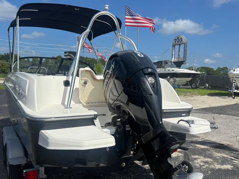 Slide: The Image of 2018 Bayliner Element F21 boat with Mercury outboard motor, parked outdoors under blue sky. - 22