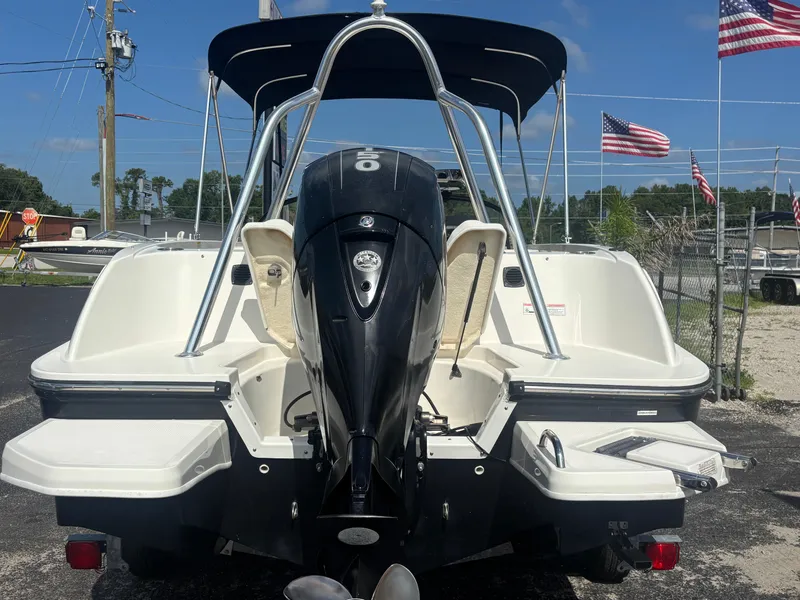Slide: The Image of 2018 Bayliner Element F21 boat with outboard motor, parked outdoors with American flags. - 23