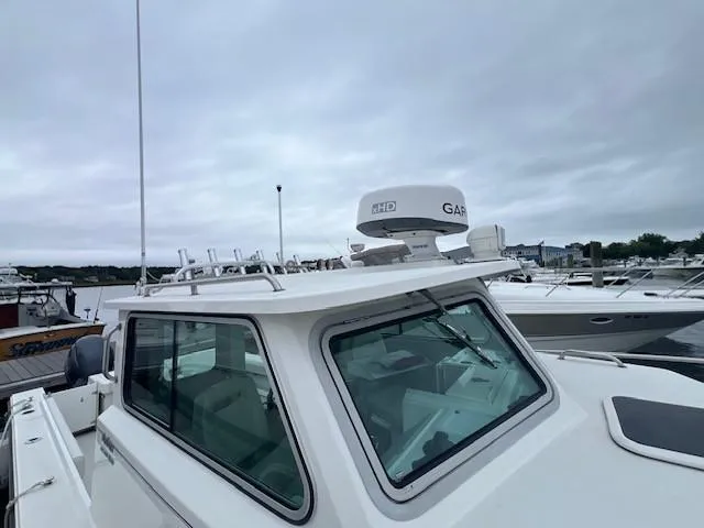 Slide: The Image of 2021 Parker 2520 XLD Sport Cabin boat docked at marina under cloudy sky. - 18
