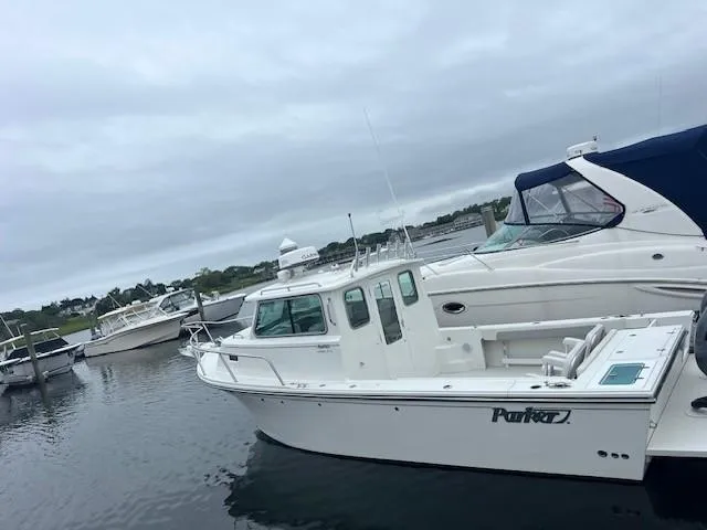 Slide: The Image of 2021 Parker 2520 XLD Sport Cabin boat docked in a marina under cloudy skies. - 23