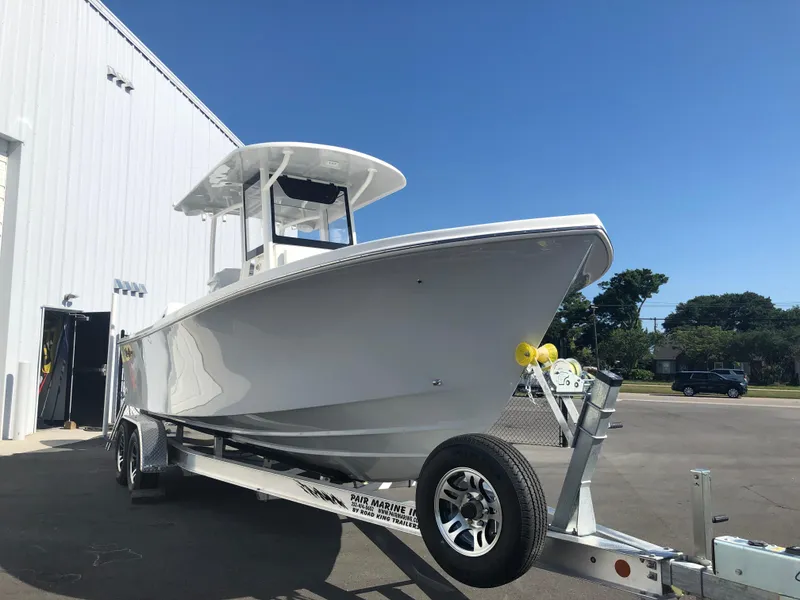 Slide: The Image of 2026 Pair Customs 24 Center Console DV boat on trailer, parked outside a building. - 16